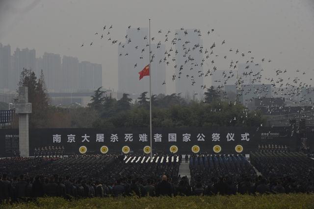 นกพิราบบินเหนือธงชาติจีนท่ามกลางประชาชนที่เข้าร่วมในพิธีรำลึกสงครามนานกิง ที่ถูกรำลึกเป็นวันรำลึกแห่งชาติเมื่อปีที่แล้ว (ภาพ รอยเตอร์ส)