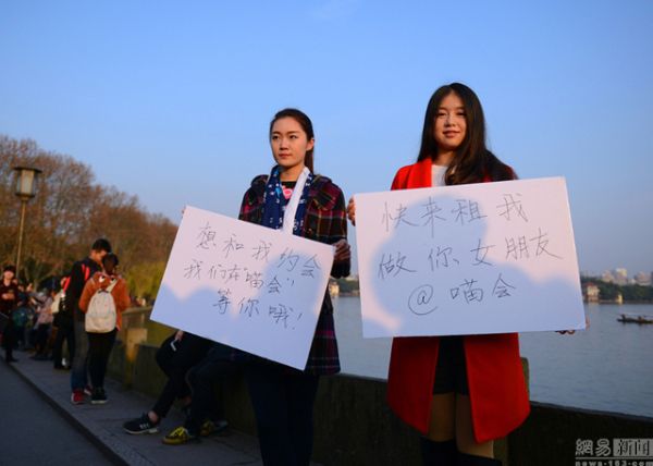 สองสาวกับป้ายข้อความเชิญชวนให้เช่า (ภาพสื่อจีน เน็ตอีส)