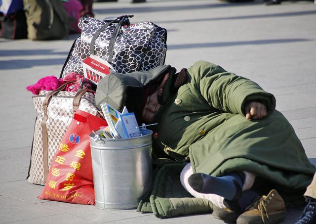 หญิงจีนงีบหลับกลางกองกระเป๋าสัมภาระที่สถานีรถไฟปักกิ่งเมื่อวันที่ 2 ก.พ. (ภาพ รอยเตอร์ส)