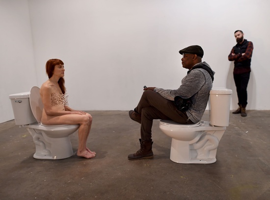 New York, State of New York: Graphic content/Conceptual artist and comedian Lisa Levy sits nude on a toilet facing a clothed participant on another toilet during Levys performance art show titled “The Artist Is Humbly Present” at the Christopher Stout Gallery January 31, 2016 in the Bushwick section of New York. AFP/Timothy A. Clary
