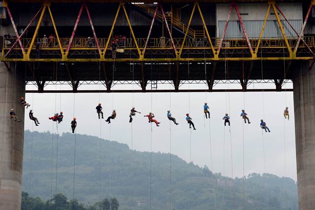 ผู้คนกำลังจับเชือกโรยตัวจากสะพานระหว่างการฝึกซ้อมช่วยชีวิตในนครฉงชิง เมื่อวันที่ 22 พ.ค. (ภาพ รอยเตอร์ส)