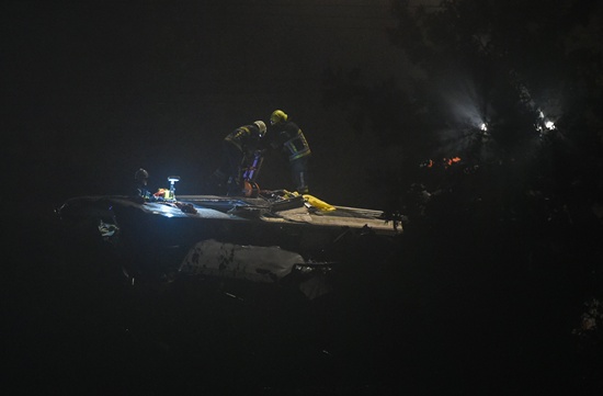 Relief wrkers work on the roof of travelers train which entered collision enters with a goods train on Sunday evening killed Hermalle-sous-Huy. three people and hurt about forty others. AFP/John Thys