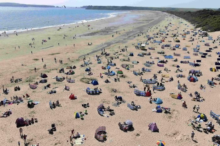 ประชาชนจำนวนมากกำลังอาบแดดพักผ่อนบนชายหาดเซาท์บีช ที่เมืองเทนบี แคว้นเวลส์ ในวันที่แสงอาทิตย์เจิดจ้า  (ภาพจากรอยเตอร์)