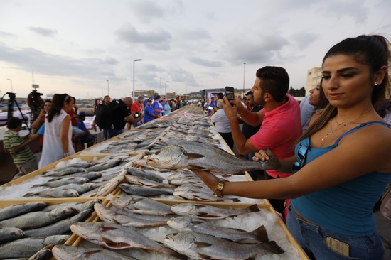 Batroun, Lebanon: A woman holds a fish as members of Lebanons Batroun Traders Association break a Guinness World Record for the largest seafood display, on September 4, 2016 in the Mediterranean coastal town of Batroun. AFP/Anwar Amro