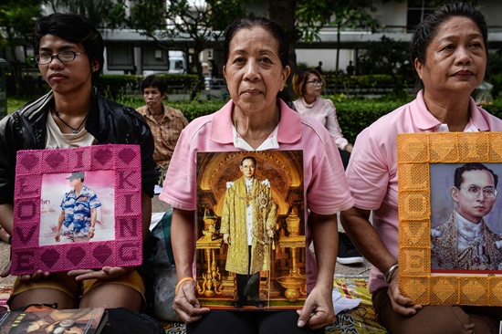 Bangkok: Well-wishers of Thailands King Bhumibol Adulyadej hold pictures bearing his image outside Siriraj Hospital, where the king is being treated, in Bangkok on October 13, 2016. AFP/Lillian Suwanrumpha