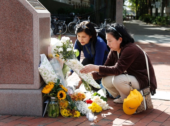 Cambridge, Massachusetts, United States: Nayara Amatquanich (C) and Anchulee Astadonwu, both tourists from Thailand, lay flowers and a candle at King Bhumibol Adulyadej Square on October 13, 2016 in Cambridge, Massachusetts. Thailands King Bhumibol Adulyadej, the worlds longest-reigning monarch, has died at the age of 88, the palace announced on October 13, leaving a divided nation bereft of a rare figure of unity. AFP/Mary Schwa