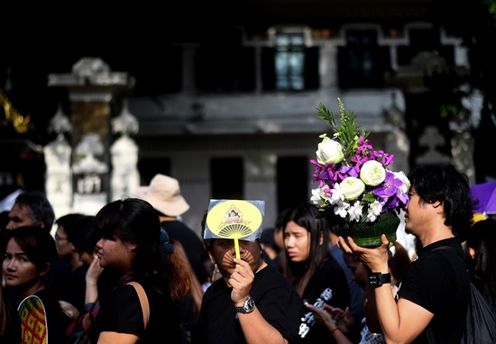 Bangkok: A man holds a picture of the late Thai King Bhumibol Adulyadej as he waits in a queue to pay respects outside the Grand Palace in Bangkok on October 15, 2016. Thailands government has warned of a national shortage of black clothing, which is flying off shelves as a distraught nation mourns beloved late King Bhumibol Adulyadej. AFP/Manan Vatsyayana