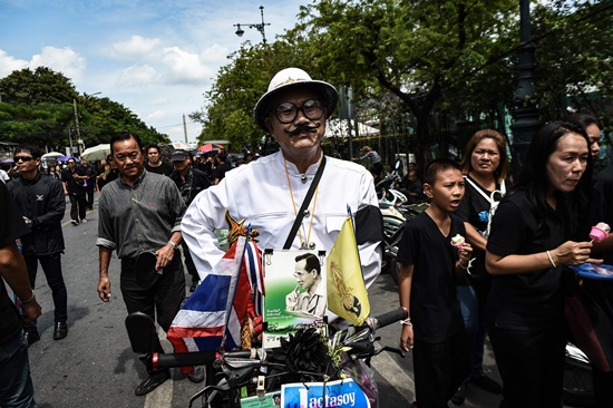Bangkok: A mourner in a traditional Thai costume displays a picture of Thai King Bhumibol Adulyadej on the front of his motorbike near the Grand Palace in Bangkok on October 22, 2016. Thailands King Bhumibol Adulyadej died at the age of 88 on October 13 after years of ill health, ending a seven-decade reign and leaving the politically divided nation without its key pillar of unity. AFP/Lillian Suwanrumpha