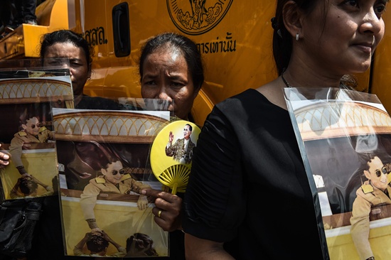 Bangkok: Mourners clad in black stand in Sanam Luang park next to the Grand Palace with images of the late Thai King Bhumibol Adulyadej in Bangkok on October 22, 2016. Thailands King Bhumibol Adulyadej died at the age of 88 on October 13 after years of ill health, ending a seven-decade reign and leaving the politically divided nation without its key pillar of unity. AFP/Lillian Suwanrumpha