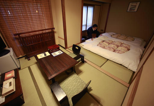 In this Jan 16, 2017 photo, Hotel Edoya Executive Director Yuta Tomura arranges a futon at the hotel in Tokyo. (AP Photo/Shizuo Kambayashi)