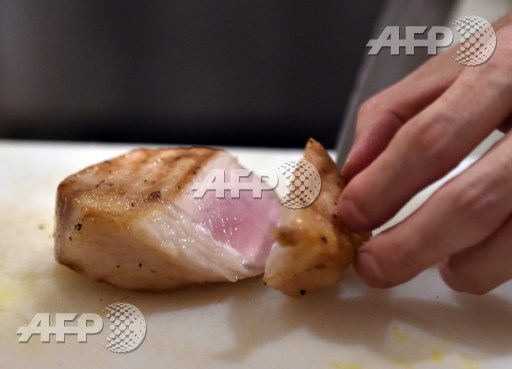 This picture taken on June 19, 2015 shows a chef slicing a cut of grilled Mangalica pork at a restaurant in Tokyo. Mangalica is a rare Hungarian bred species of pig. AFP PHOTO/Yoshikazu Tsuno  