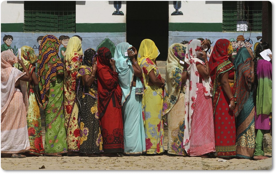  ผู้มีสิทธิ์ออกเสียงหญิงอินเดียที่สวมเสื้อผ้าสีฉูดฉาดละลานตา ที่ต่างคลุมศรีษะ กำลังยืนต่อแถวเพื่อรอการลงคะแนนเลือกตั้งบริเวณชานเมืองเมืองอัลลาฮาบัด( Allahabad )รัฐอุตรประเทศ( Uttar Pradesh state) ในวันพฤหัสบดี(23 ก.พ) (ภาพเอพี)