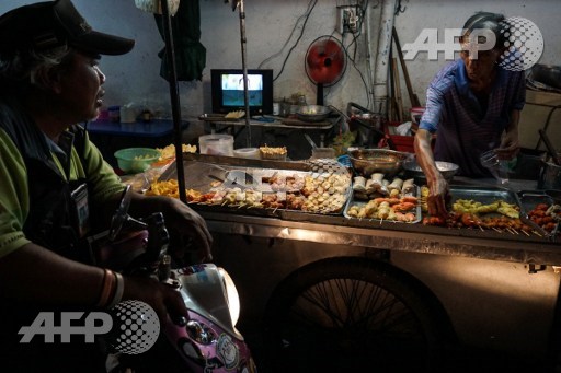 This photo taken on April 17, 2017 shows a street food vendor talking to a customer in the Phrakanong district of Bangkok. Street food stalls will be banned from all of Bangkoks main roads under a clean-up crusade, a city hall official said Tuesday, prompting outcry and anguish in a food-obsessed capital famed for its spicey roadside cuisine. Lillian Suwanrumpha/AFP