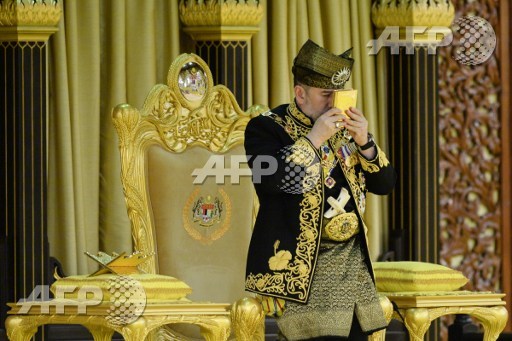 This handout photo taken and released by Malaysias Department of Information on April 24, 2017 shows the 15th king of Malaysia, King Muhammad V, kissing a copy of the Koran during his coronation at the National Palace in Kuala Lumpur. Asraf Affandi Azlan/Department of Information/AFP