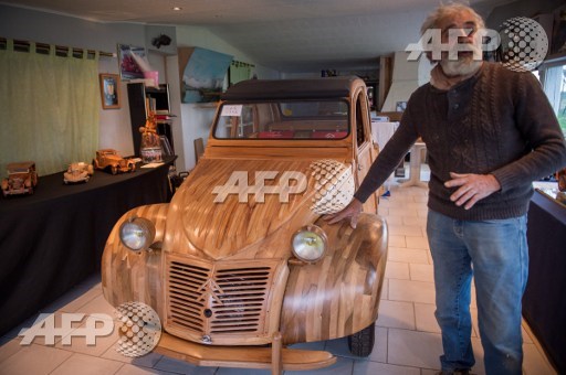 This photo taken on March 21, 2017 shows French cabinetmaker Michel Robillard posing next to his handbuilt wooden 2CV Citroen Car built as an exact one/one replica, near Loches, Central France. Guillaume Souvant/AFP
