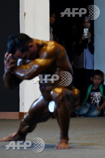 Women take photographs of a bodybuilder performing onstage during the Mr. Malaysia 2017 bodybuilding competition in Puchong, outside Kuala Lumpur, on May 21, 2017. Manan Vatsyayana/AFP