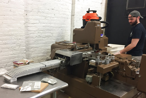 This April 28, 2017 photo shows William Widmaier operating a machine that wraps chocolate bars at Raaka Chocolate in the Red Hook section of Brooklyn, N.Y. Raaka is one of a number of stops on A Slice of Brooklyn chocolate tour, which offers chocolate samples to taste along with visits to different neighborhoods and insights into how some of the businesses on the tour got started. (AP Photo/Beth J. Harpaz) 