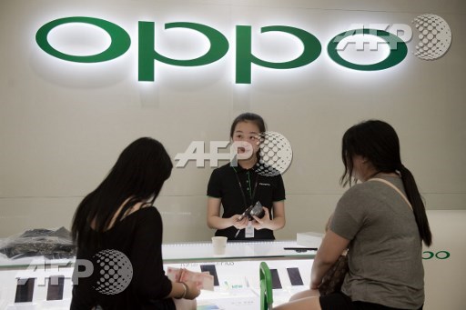 In this picture taken on May 9, 2017, customers buy a smartphone at an Oppo shop in Shenzhen. Oppo, which started out making DVD players in the southern manufacturing hub of Dongguan over a decade ago, has exploded in popularity to become one of the top brands in China. Its market share more than doubled last year to 16.8 percent -- beating all of its competitors. Nicolas Asfouri/AFP