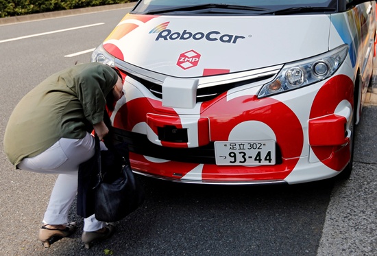 A woman looks at ZMP Incs RoboCar MiniVan, a self-driving Toyota Estima Hybrid car, after a joint news conference between ZMP and Hinomaru Kotsu Co in Tokyo, Japan June 15, 2017. REUTERS/Toru Hanai
