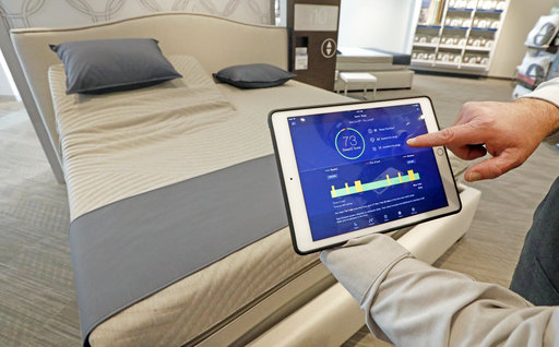 In this Friday, July 7, 2017, photo, Sleep Number store manager Lee Pulliam demonstrates how the companys sleep technology tracks your sleeping patterns, in addition to the other features of the Sleep Number 360 Smart Bed, including a foot warming element, adjustable side comfort, head and foot raising capability and an analysis of how well a person slept. (AP Photo/Rogelio V. Solis)