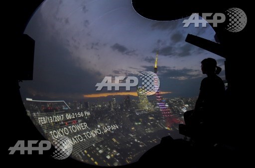 A journalist looks at 8K video images projected on a 3.4-meter-high and 2.6-meter-deep dome-type widescreen as they experience a new virtual reality (VR) motion ride system, during a press preview in Tokyo on July 18, 2017. Toru Yamanaka/AFP