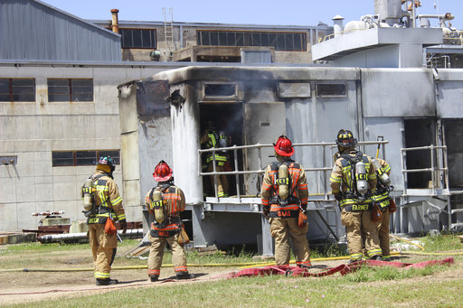 In this photo provide by the Bryan, Texas Fire Department, taken April 29, 2014, Bryan Texas firefighters stand outside the Bryan Texas Utilities Power Plant following an explosion and fire. (Bryan, Texas Fire Department via AP)