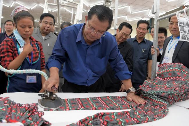 <br><FONT color=#000033>นายกรัฐมนตรีฮุนเซน (กลาง) โชว์รีดผ้าที่โรงงานแห่งหนึ่งย่านชานกรุงพนมเปญ วันที่ 30 ส.ค. -- Agence France-Presse/Stringer.</font></b>