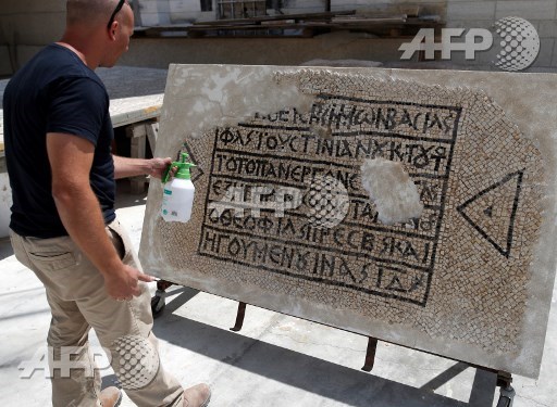 An archaeologist works on part of a 1,500-year-old mosaic floor bearing the names of Byzantine Emperor Justinian, at the Rockefeller Museum in Jerusalem, on August 23, 2017, after they unearth a portion of ancient mosaic near the citys Damascus Gate. Ahmad Gharabli/AFP