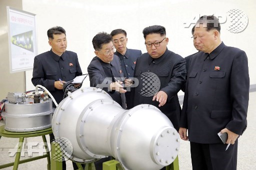 (FILES) This undated file photo released by North Koreas official Korean Central News Agency (KCNA) on September 3, 2017 shows North Korean leader Kim Jong-Un (C) looking at a metal casing with two bulges at an undisclosed location. Japan on September 6, 2017 again upgraded its estimated size of North Koreas latest nuclear test to a yield of around 160 kilotons -- more than ten times the size of the Hiroshima bomb. STR/KCNA via KNS/AFP