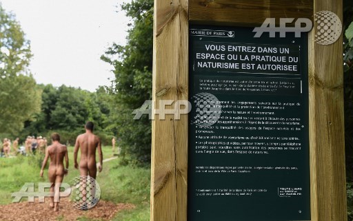 Two naked persons walk past a sign reading you are entering a space where the practise of naturism is authorised at a newly opened space for naturists at the Bois de Vincennes park in Paris on August 31, 2017. The space will be open daily until October 15th. Bertrand Guay/AFP