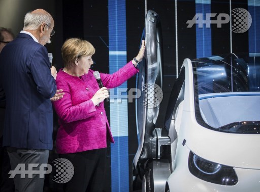 German Chancellor Angela Merkel and CEO of German car maker Daimler AG and head of Mercedes-Benz cars Dieter Zetsche stand next to an electric Smart concept car as they visit the booth of Mercedes during her inauguration tour of the Internationale Automobil Ausstellung (IAA) auto show on September 14, 2017 in Frankfurt am Main, western Germany. Chancellor Angela Merkel will formally open the Frankfurt car show on Thursday, where she will face a delicate balancing act between defending millions of duped diesel owners without alienating Germanys most powerful industry. Frank Rumpenhorst/dpa/AFP