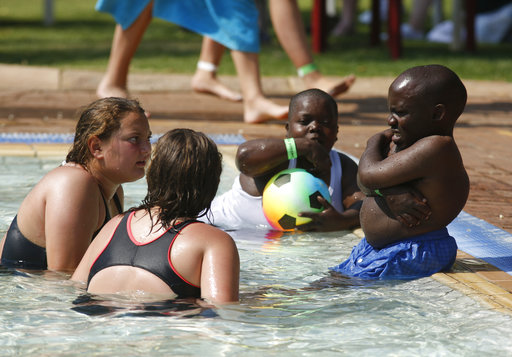 People relax in a pool at the Weesgerus holiday resort during a weekend dwarf festival in Modimolle, South Africa, Saturday, Sept. 9, 2017. (AP Photo/Denis Farrell)