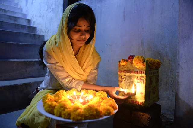 หญิงชาวอินเดียจุดโคมไฟดินเผา หรือ ‘ดิยาส’ ที่บ้านของเธอหนึ่งวันก่อนเทศกาลดิวาลีในไฮเดอร์ราบัด (18 ต.ค.)