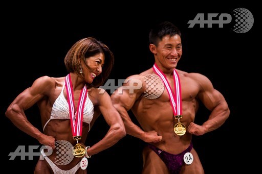 In this picture taken on October 9, 2017, winning Japanese bodybuilder in the womens category Megumi Sawada and winner in the mens category Masashi Suzuki pose on stage during the Japan bodybuilding championships in Tokyo. Behrouz Mehri/AFP