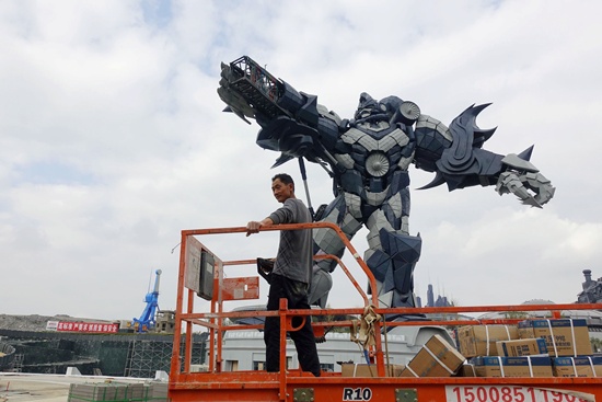  A worker rides on a cart in front of a giant robot statue at the Oriental Science Fiction Valley theme park in Guiyang, Guizhou province, China November 16, 2017. Picture taken November 16, 2017. REUTERS/Joseph Campbell