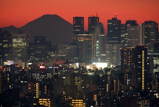 This picture taken on December 3, 2017 shows Japans highest mountain, Mount Fuji at 3,776 meters (12,388 feet), seen behind skyscrapers in Tokyos Shinjuku area during sunset. Japan is growing twice as fast as previously estimated, official data showed on December 8, 2017, with the worlds third-largest economy posting its longest string of gains in more than two decades. Kazuhiro Nogi/AFP