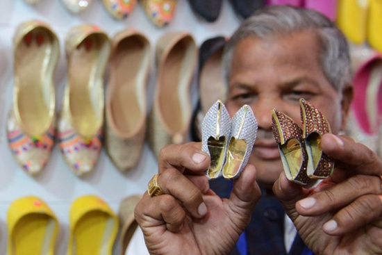 Indian exhibitor Budh Ram (C) holds his handmade miniature shoes known as Punjabi Jutti during The Punjab International Trade Expo PHD (PITEX) 2017 Trade Fair in Amritsar on December 7, 2017. Narinder Nanu/AFP