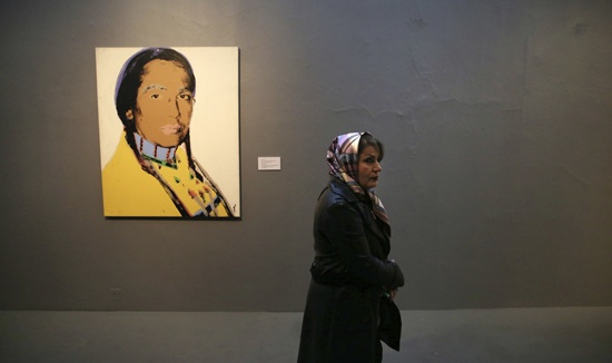 FILE - In this file photo taken on Martch 9, 2017, a woman walks past an artwork of American artist Andy Warhol, The American Indian Series (Russell Means), at Museum of Contemporary Art in Tehran, Iran. Police in Irans capital say they will no longer arrest women for failing to observe the Islamic dress code imposed since the 1979 revolution. (AP Photo/Vahid Salemi, File)