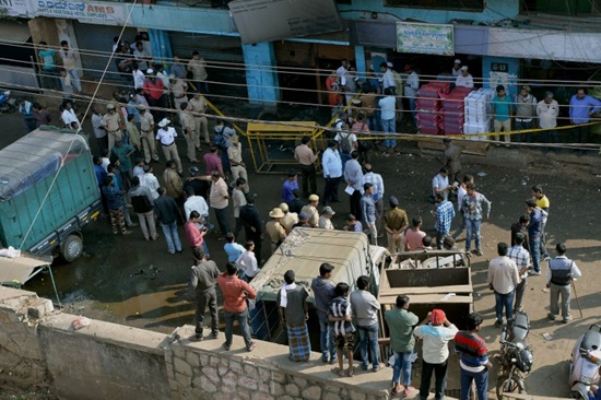 Bystanders and members of the media watch as Indian police officials cordon off the scene where fire broke out at a bar and restaurant in Bangalore on January 8, 2018. Five workers were killed early January 8 when a bar and restaurant in southern India caught fire, police said, less than two weeks after a blaze at another eatery killed 14. Police said an electrical short-circuit probably caused the fire at the Kailash Bar & Restaurant in the southern technology hub of Bangalore. Manjunath Kiran/AFP