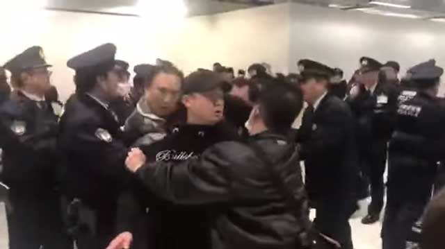 เหตุวุ่นวายระหว่างตำรวจกับกลุ่มนักท่องเที่ยวที่ตกค้างสนามบิน ได้ดำเนินไปจนถึงขั้นวิวาท และนักเดินทางชาวจีนบางคนเริ่มร้องเพลงชาติของตน (ภาพจากคลิปฯ)
