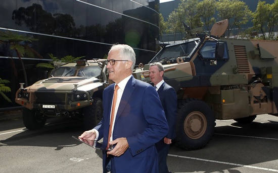 Australia Prime Minister Malcolm Turnbull walks in front of military trucks during a visit to Thales Underwater Systems in Sydney, Monday, Jan. 29, 2018. The government announced a new strategy to boost Australia into the ranks of the top 10 defense industry exporting countries within a decade through arms sales to liked-minded nations and with safeguards to keep weapons out of the hands of rogue regimes. (Daniel Munoz/AAP Image via AP)