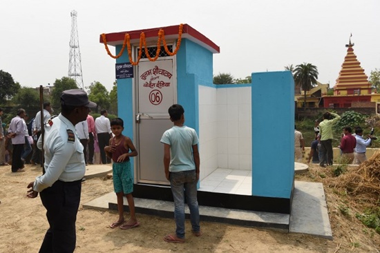 This photo taken on April 8, 2018, shows a private security guard and villagers gathering around a newly built public toilet by Boeing India, under its Corporate Social Responsibility (CSR) activity, at Sarisabpahi Village in Madhubani district in Bihar. Prakash Singh/AFP