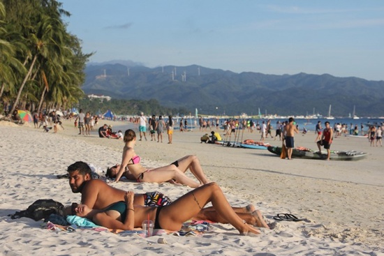 Tourists relax in a beach in Boracay, Malay town, in central Philippines on April 17, 2018, ahead of its closure. The Philippines is set to deploy hundreds of riot police to top holiday island Boracay to keep travellers out and head off potential protests ahead of its six-month closure to tourists, the government said April 17. STR/AFP