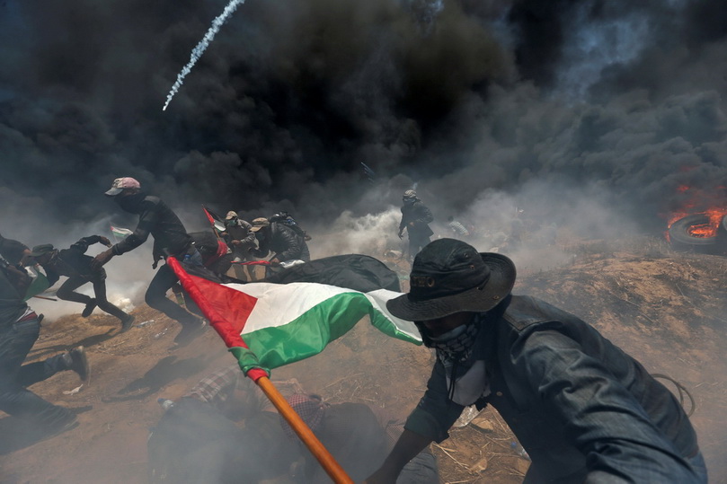 ผู้ประท้วงชาวปาเลสไตน์วิ่งหลบกระสุนและแก๊สน้ำตาที่ถูกยิงมาจากฝั่งอิสราเอล ระหว่างการชุมนุมประท้วงการย้ายสถานทูตสหรัฐฯ ไปยังนครเยรูซาเลม เมื่อวันที่ 14 พ.ค. 
