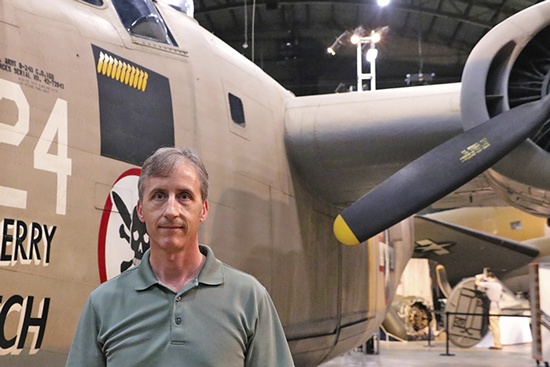 This May 16, 2018 photo shows University of Illinois professor Scott Althaus poses with a World War II B-24 bomber at the National Museum of the Air Force at Wright-Patterson Air Force Base in Dayton, Ohio. Althaus is a cousin of Lt. Thomas Kelly, a bombardier aboard a B-24 bomber that was was shot down in Hansa Bay in what is now Papua New Guinea during World War II. (Kyra Althaus via AP)