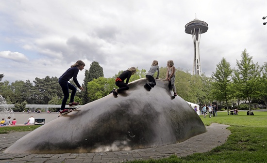 In this photo taken May 20, 2018, children scramble atop a whale sculpture in view of the Space Needle at the Seattle Center in Seattle. (AP Photo/Elaine Thompson)