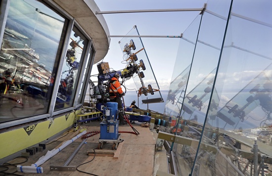 FILE - In this March 20, 2018, file photo, a one-ton glass panel is moved into position on the Space Needles observation deck in Seattle. (AP Photo/Elaine Thompson)