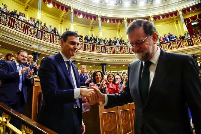 เปโดร ซานเชซ ผู้นำโซเชียลิสต์ ว่าที่นายกรัฐมนตรีคนใหม่ของสเปน (ซ้าย) จับมือกับ มาเรียโน ราฮอย(ขวา) ว่าที่อดีตนายกรัฐมนตรี หลังเสร็จสิ้นศึกอภิปรายไม่ไว้วางใจฝ่ายหลังในรัฐสภาสเปน ในกรุงมาดริดวันศุกร์(1มิ.ย.) 