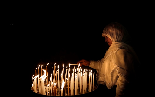 ผู้ประกอบพิธีชาวคริสต์คนหนึ่งกำลังจุดเทียนไขภายในโบสถ์ Holy Sepulchre ในเมืองเก่าของเยรูซาเล็ม เมื่อวันที่ 24 มกราคม