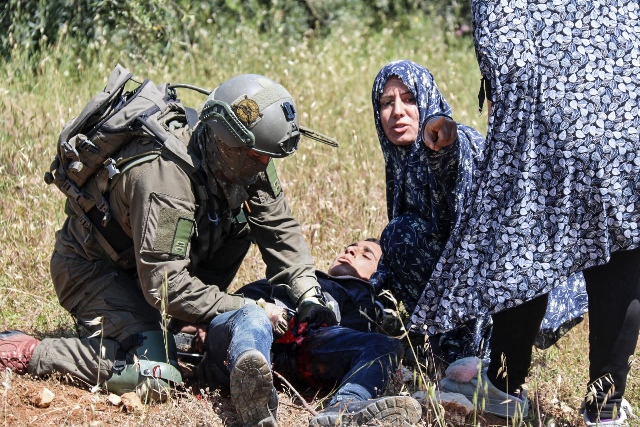 ภาพทหารอิสราเอลกำลังทำการปฐมพยาบาล โอซามา อาลี อัลบาดัน ชาวปาเลสไตน์วัย 16 ปี หลังเขาถูกยิงโดยกองกำลังอิสราเอล